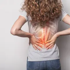 Kobieta z bólem kręgosłupa, symbolizującym powrót do pracy po złamaniu kręgosłupa.