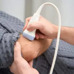 Ortopeda wykonuje badanie USG nadgarstka pacjenta, co jest kluczowe w diagnostyce schorzeń układu ruchu.