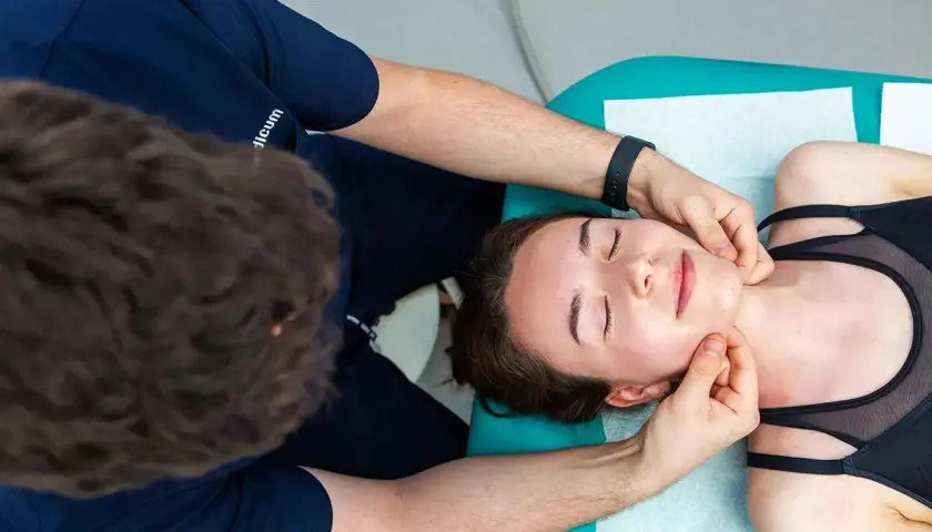 Fizjoterapeuta wykonuje masaż twarzy, co jest częścią rehabilitacji stomatologicznej.