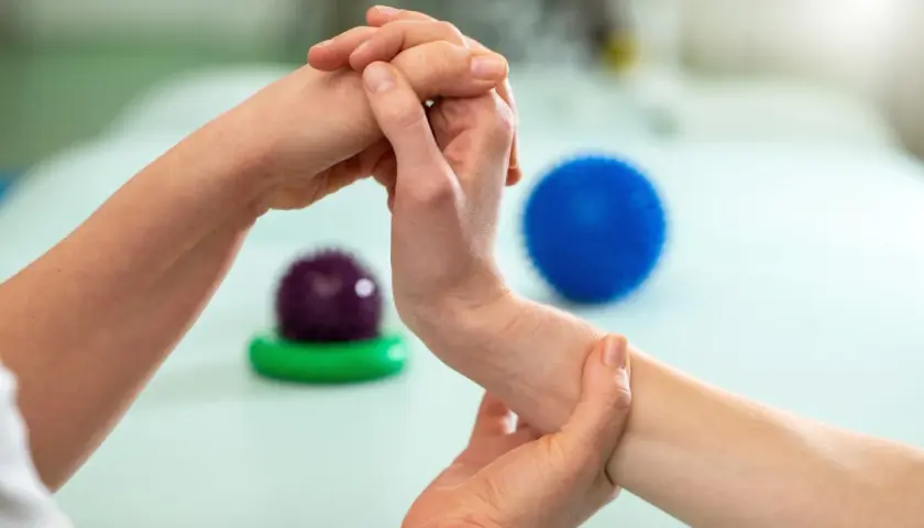 Fizjoterapeuta wykonuje ćwiczenia na palec trzaskający, pomagając pacjentowi odzyskać sprawność.