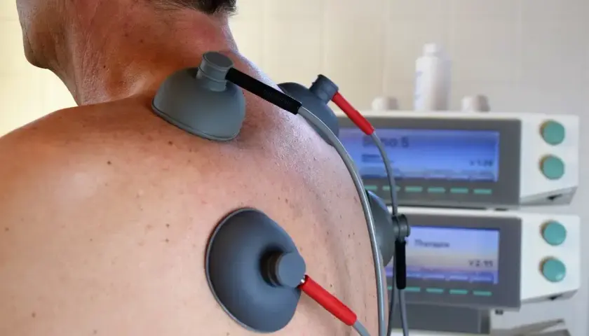 Elektrody TENS na plecach pacjenta. Choć zabieg jest bezpieczny, warto znać potencjalne prądy TENS skutki uboczne.