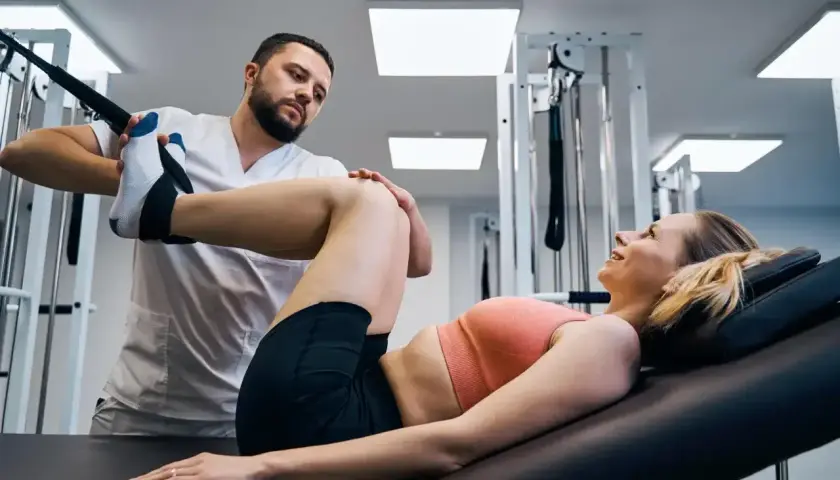 Fizjoterapeuta pomaga pacjentce w ćwiczeniach rehabilitacyjnych. Osteopata wspiera powrót do zdrowia.