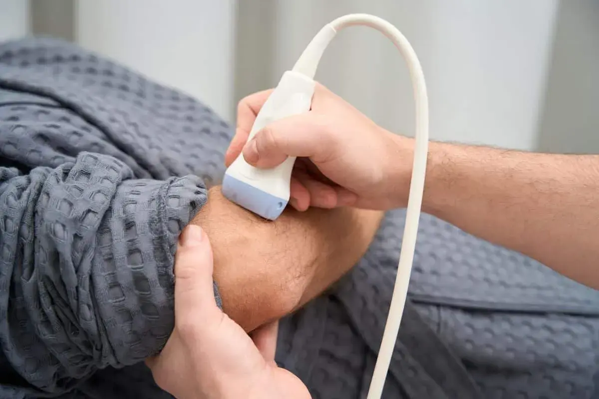 Ortopeda wykonuje badanie USG nadgarstka pacjenta, co jest kluczowe w diagnostyce schorzeń układu ruchu.