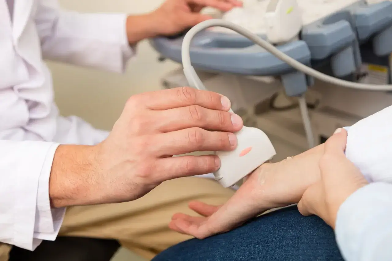 Lekarz wykonuje USG nadgarstka, aby zdiagnozować przyczynę bólu.